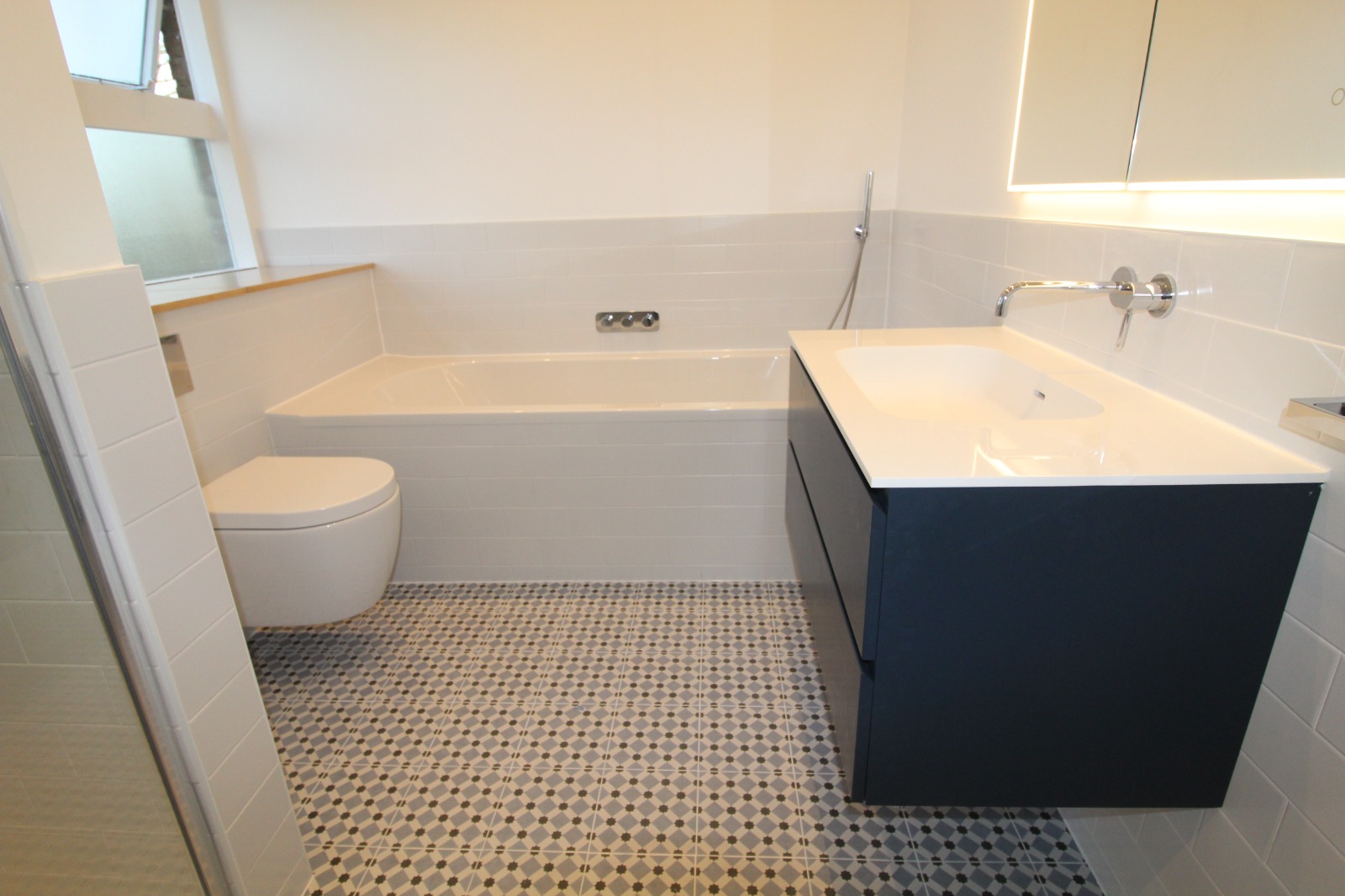 Family bathroom with navy vanity and patterned floor tiles